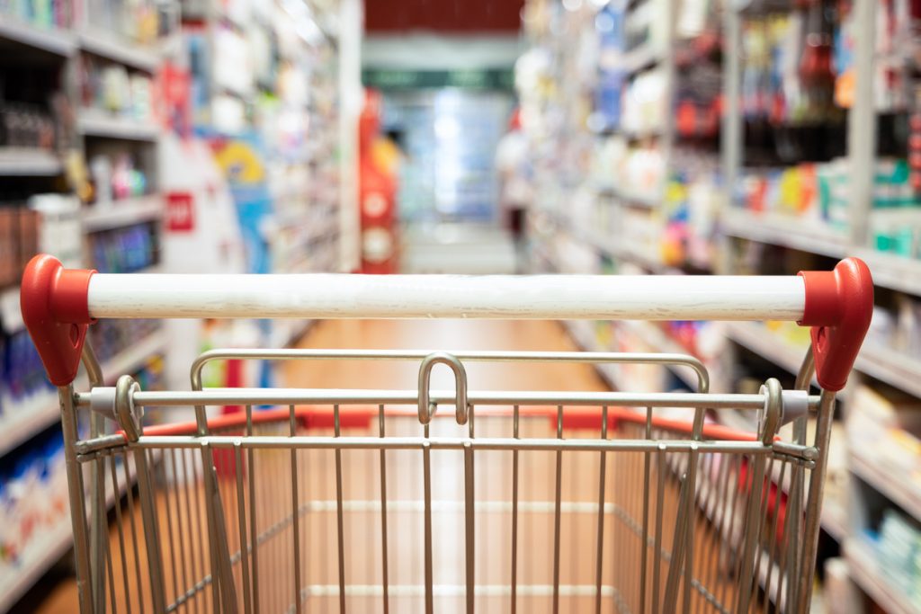 Close-up of a shopping trolley in a supermarket aisle.