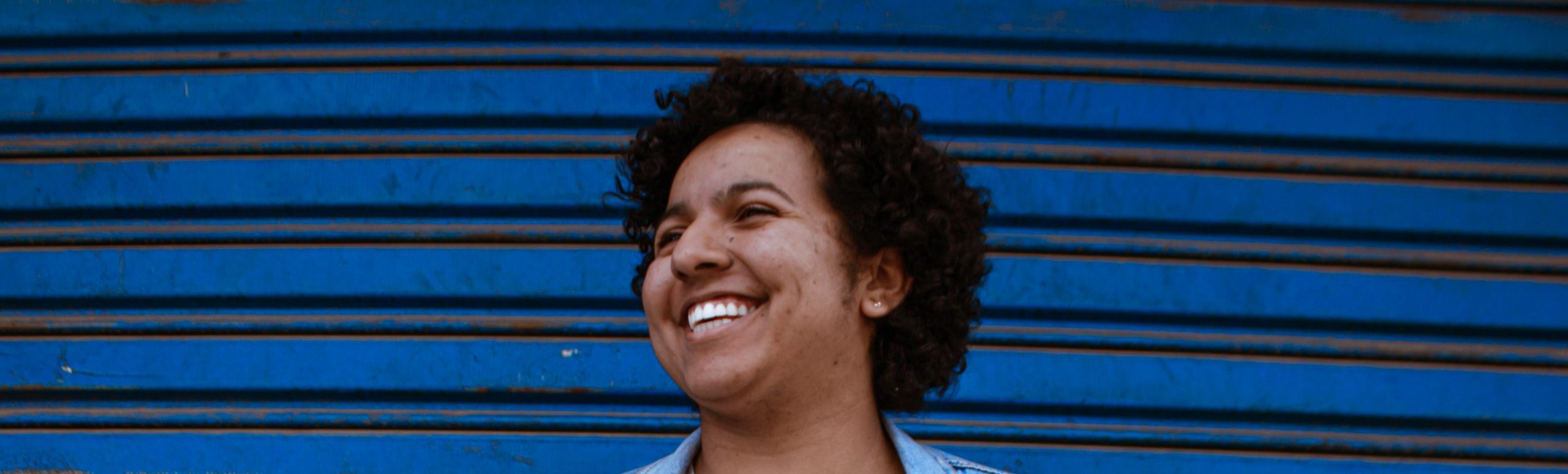 A woman smiling in front of a blue shutter