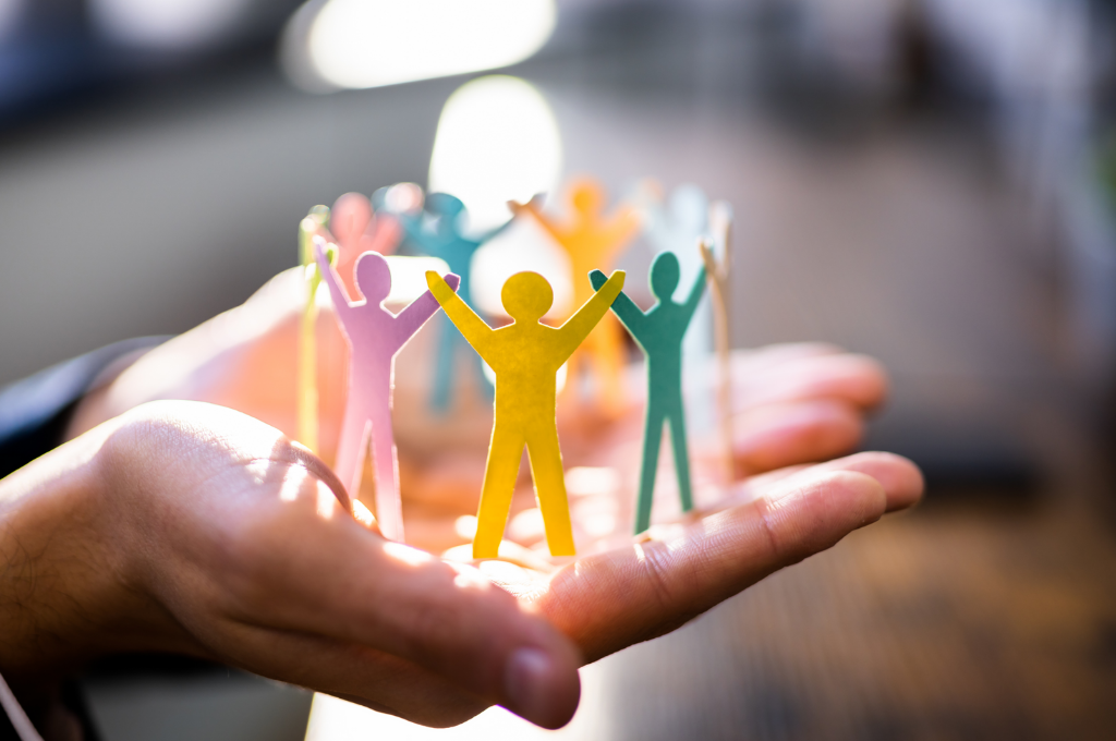 a paper cutout of people holding hands, in someones hands
